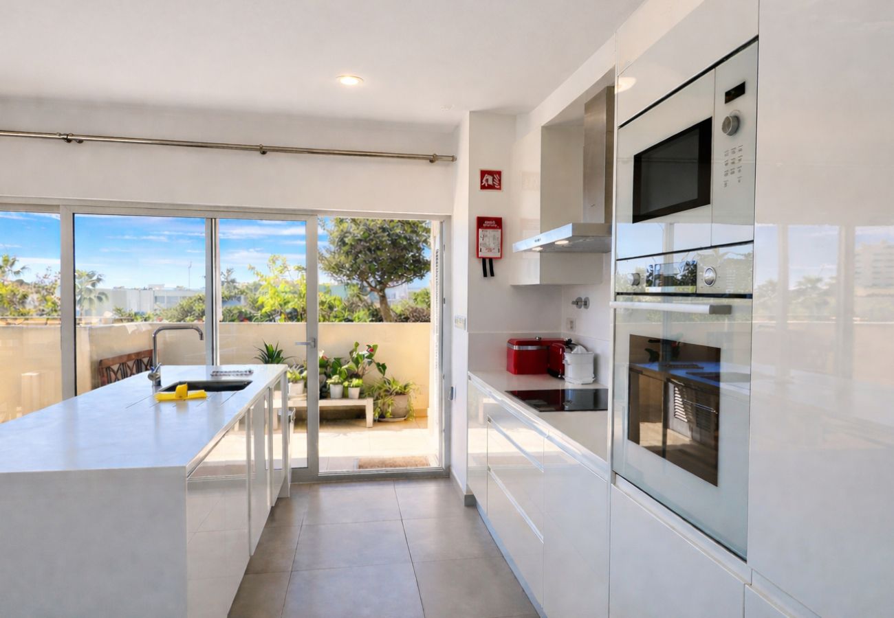 Cozinha moderna e luminosa com acesso ao terraço em apartamento em Albufeira 